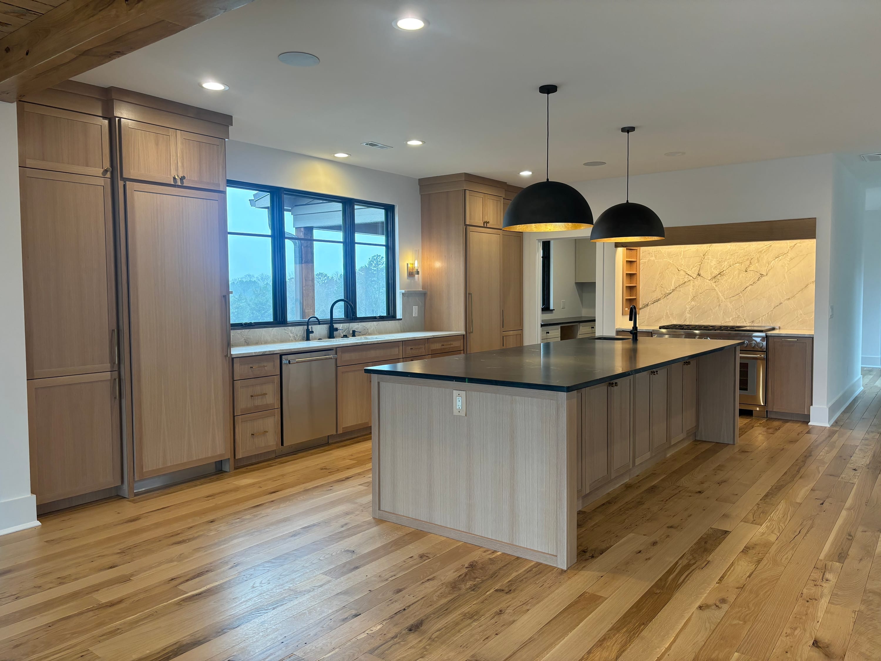 Open white oak kitchen with a long island and black countertops