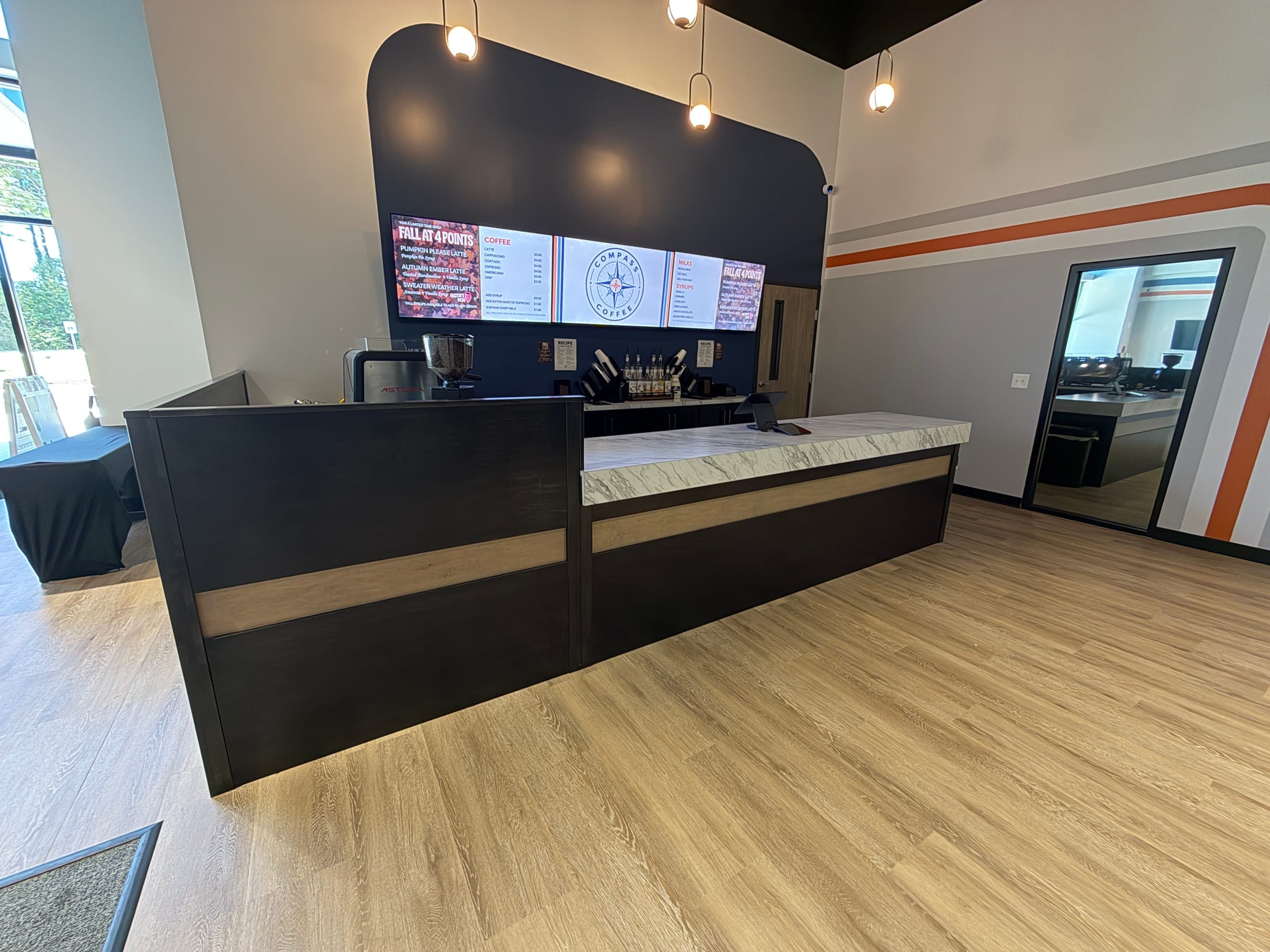 Commercial coffee bar with a dark stained counter under pendant lights